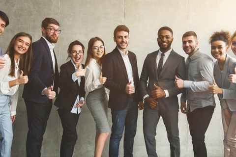 group of several individuals wearing business casual to formal wear giving a thumbs up for a group photo.